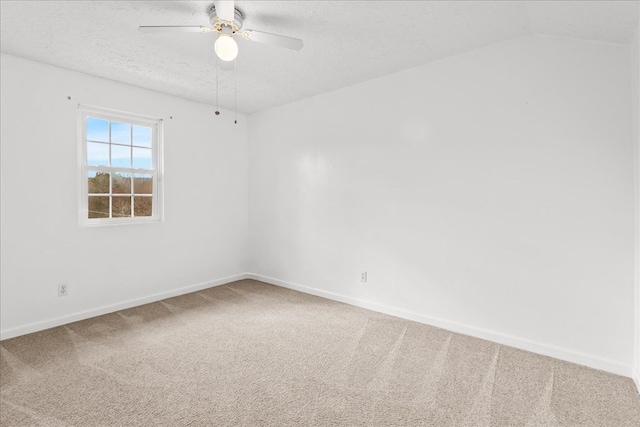 unfurnished room with lofted ceiling, a textured ceiling, carpet, baseboards, and ceiling fan