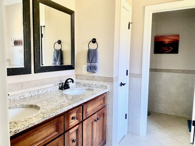 full bath with double vanity, a sink, tile walls, and tile patterned floors