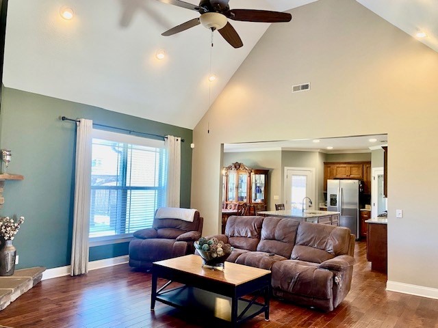 living room with high vaulted ceiling, dark wood-style flooring, visible vents, and baseboards