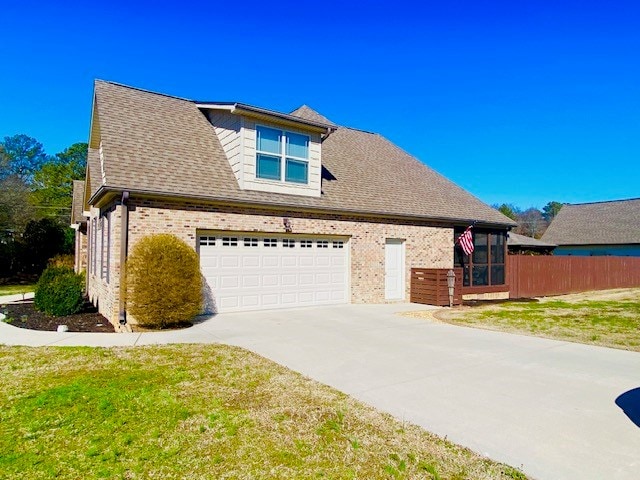 view of front of house featuring driveway, roof with shingles, fence, a front lawn, and brick siding