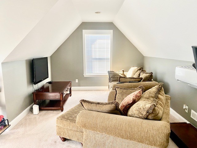 carpeted living room featuring lofted ceiling, a wall mounted AC, visible vents, and baseboards