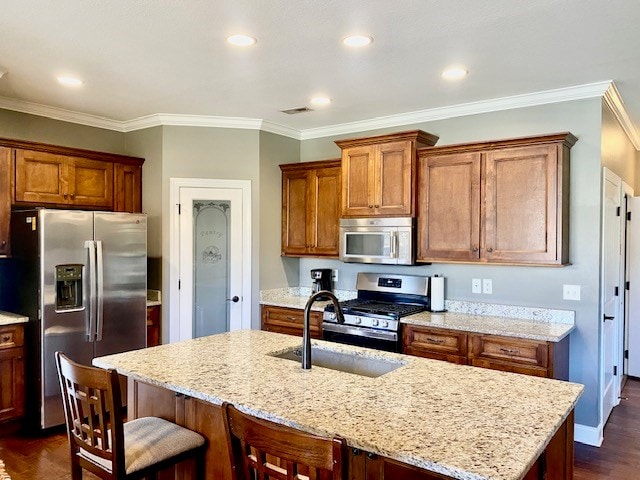 kitchen featuring a sink, visible vents, appliances with stainless steel finishes, brown cabinets, and dark wood finished floors