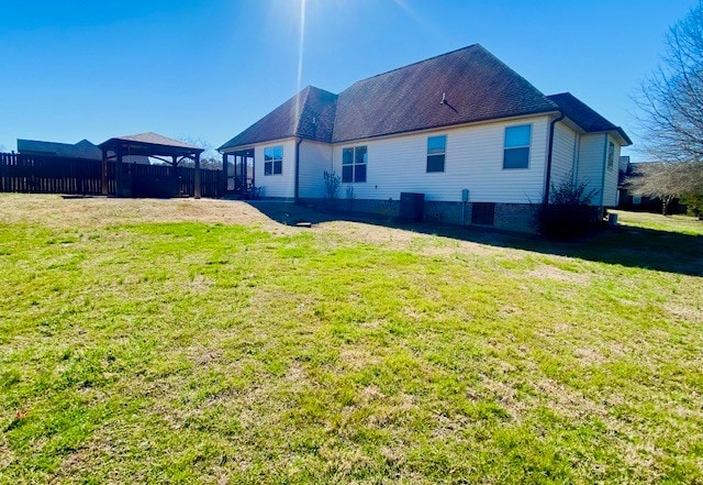 rear view of house with a lawn, a gazebo, and fence