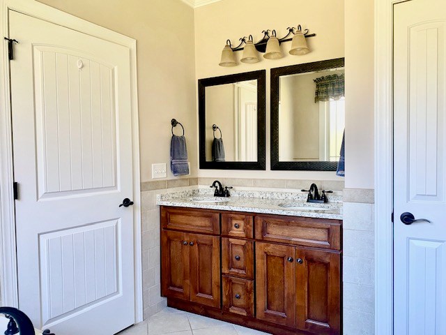 full bathroom with double vanity, tile walls, a sink, and tile patterned floors