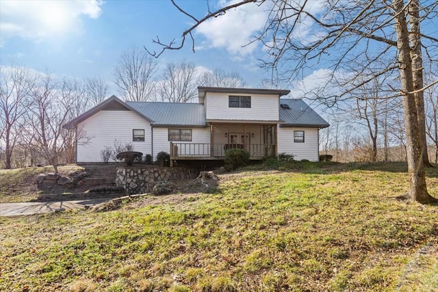 back of house with metal roof, a wooden deck, and a lawn