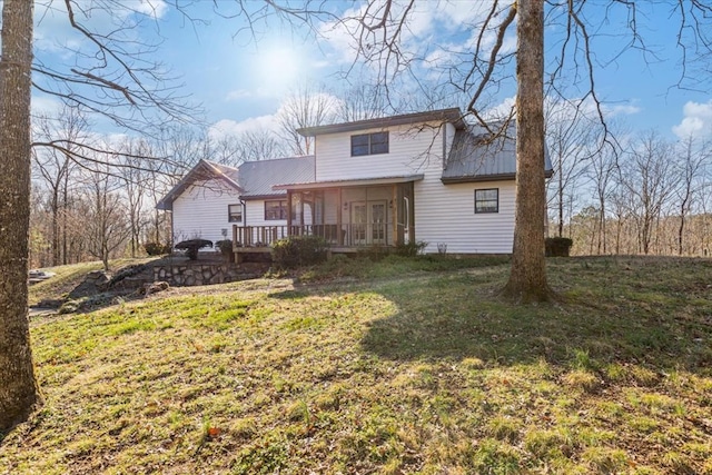 back of house with metal roof, a lawn, and a wooden deck