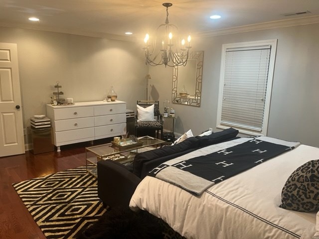 bedroom featuring an inviting chandelier, ornamental molding, and dark hardwood / wood-style flooring