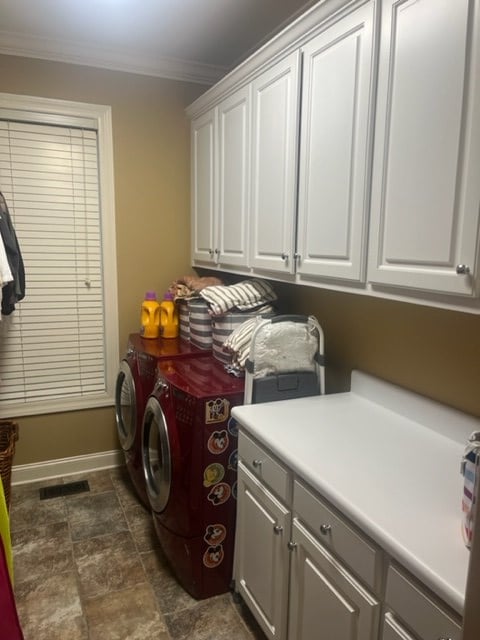 clothes washing area with washer and dryer, ornamental molding, and cabinets