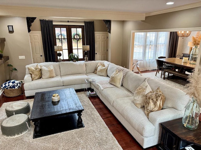 living room featuring crown molding, dark hardwood / wood-style floors, a chandelier, and french doors