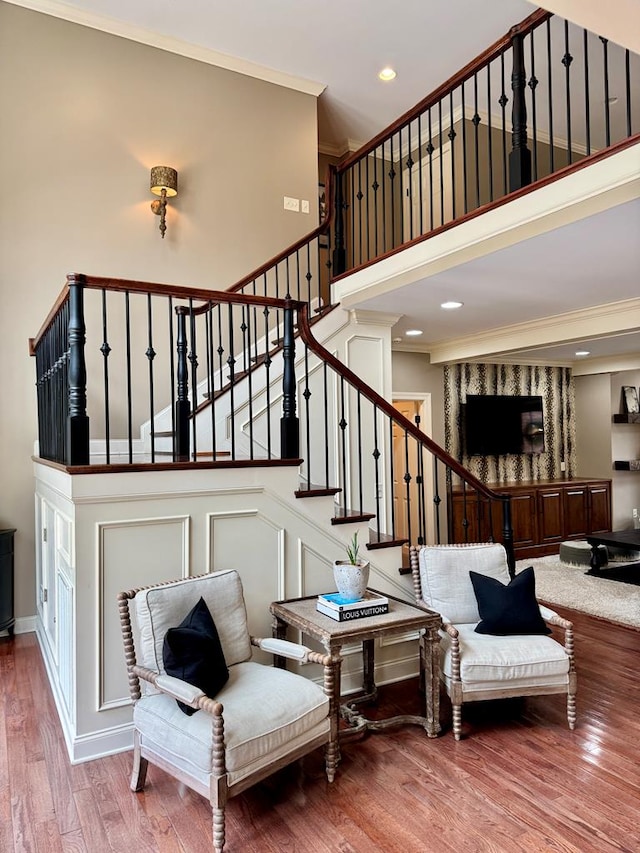 stairway featuring crown molding, a towering ceiling, and hardwood / wood-style floors