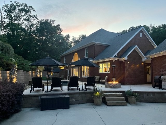 back house at dusk with a patio area and a fire pit