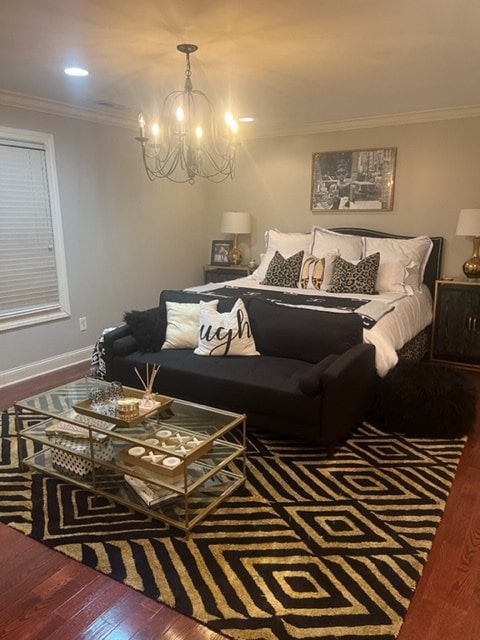 bedroom featuring hardwood / wood-style flooring, ornamental molding, and a chandelier