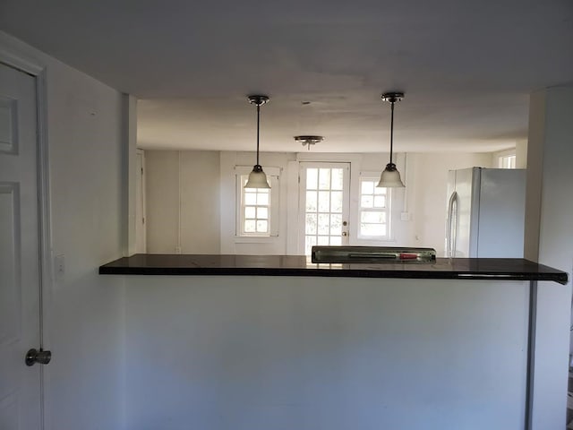 kitchen featuring hanging light fixtures, fridge, and kitchen peninsula