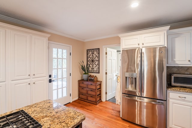 kitchen featuring light stone counters, stainless steel fridge, and white cabinets