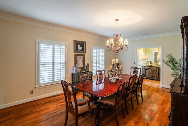 dining space featuring ornamental molding, hardwood / wood-style floors, a textured ceiling, and an inviting chandelier