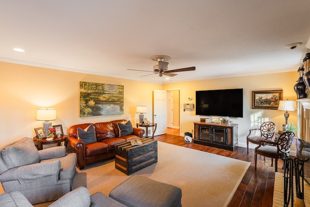 living room featuring a fireplace, crown molding, dark wood-type flooring, and ceiling fan