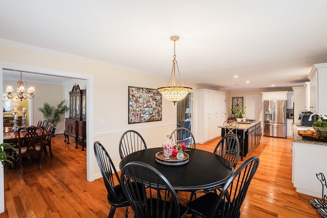 dining area with crown molding, an inviting chandelier, and light hardwood / wood-style flooring