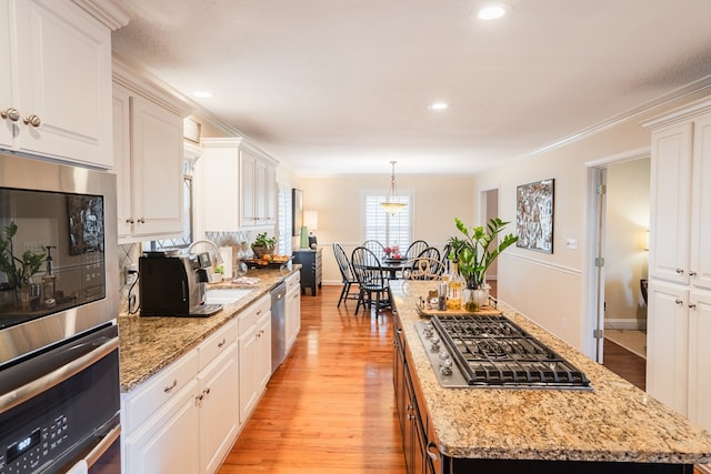 kitchen featuring white cabinetry, decorative light fixtures, a center island, and appliances with stainless steel finishes