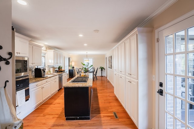 kitchen with light stone counters, stainless steel appliances, a center island, and white cabinets