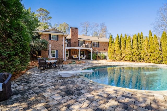 view of pool with a diving board and a patio