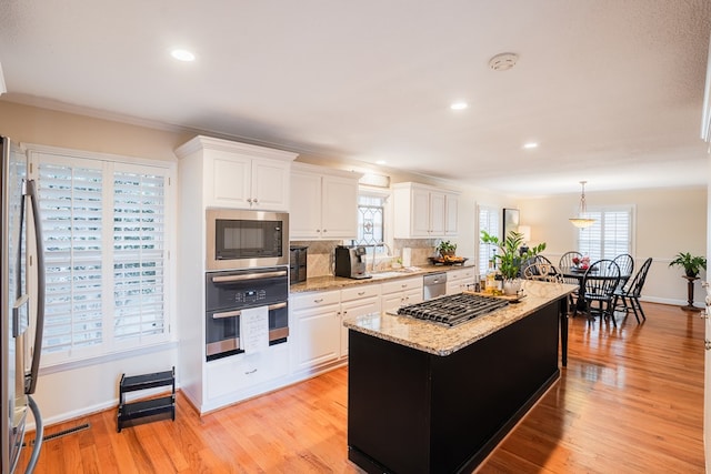 kitchen featuring appliances with stainless steel finishes, a center island, pendant lighting, and white cabinets