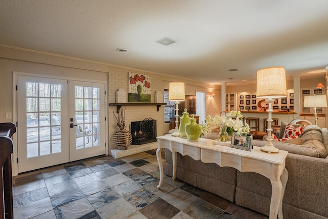 living room featuring crown molding, a textured ceiling, a fireplace, and french doors