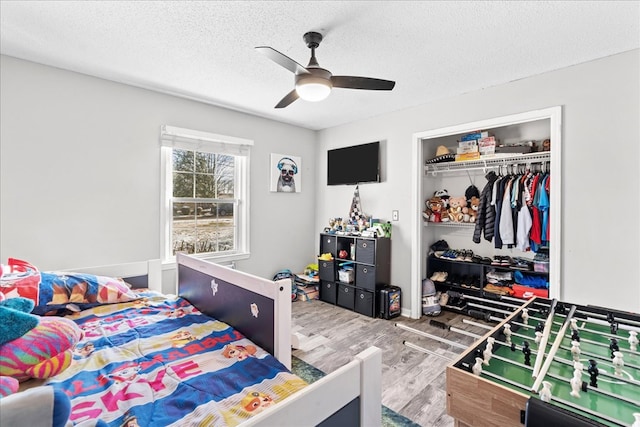 bedroom with hardwood / wood-style flooring, a closet, ceiling fan, and a textured ceiling