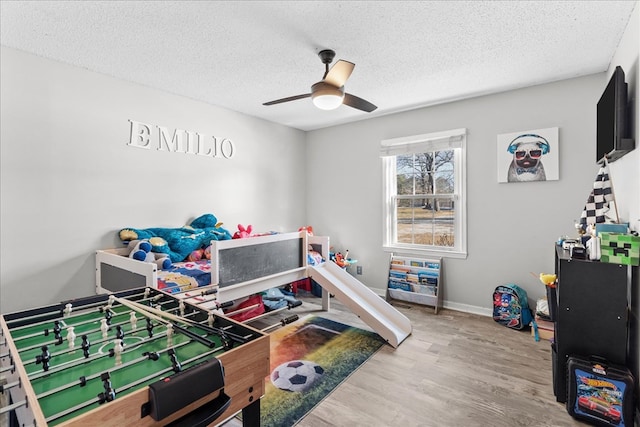 game room featuring ceiling fan, hardwood / wood-style floors, and a textured ceiling