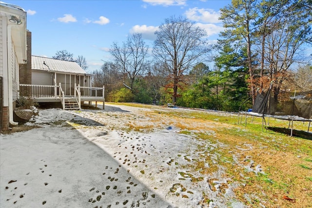 view of yard with a deck, a trampoline, and a sunroom