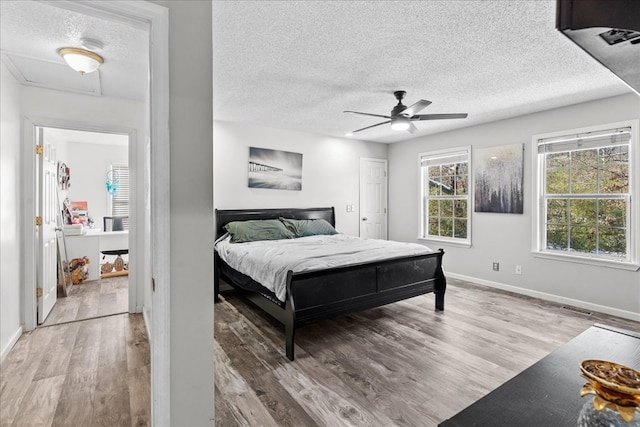 bedroom with ceiling fan, a textured ceiling, and light wood-type flooring