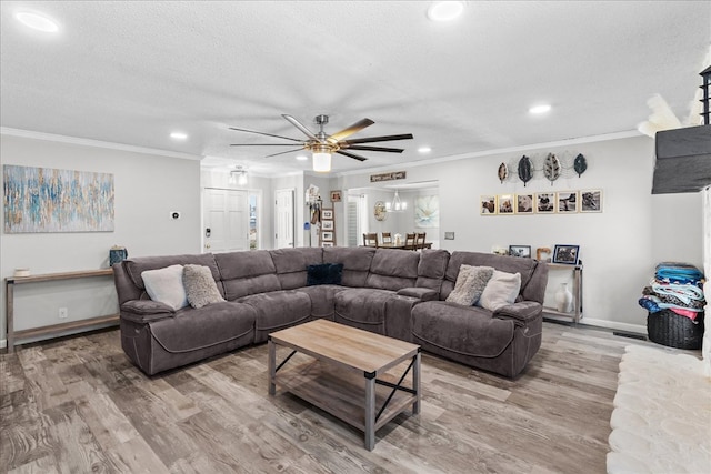 living room with hardwood / wood-style flooring, ceiling fan, ornamental molding, and a textured ceiling