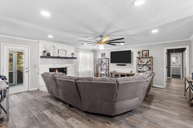 living room with ornamental molding, a fireplace, hardwood / wood-style floors, and a textured ceiling