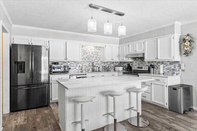 kitchen featuring white cabinetry, a kitchen bar, stainless steel appliances, and a kitchen island