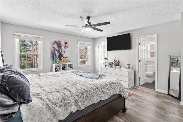 bedroom featuring ceiling fan, a textured ceiling, light wood-type flooring, and ensuite bath