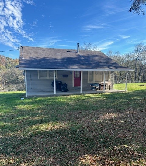 rear view of property featuring a patio and a lawn