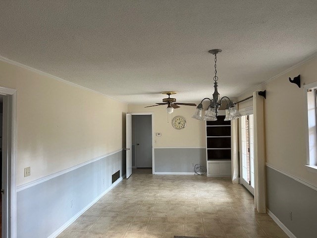 empty room with ceiling fan with notable chandelier, ornamental molding, and a textured ceiling