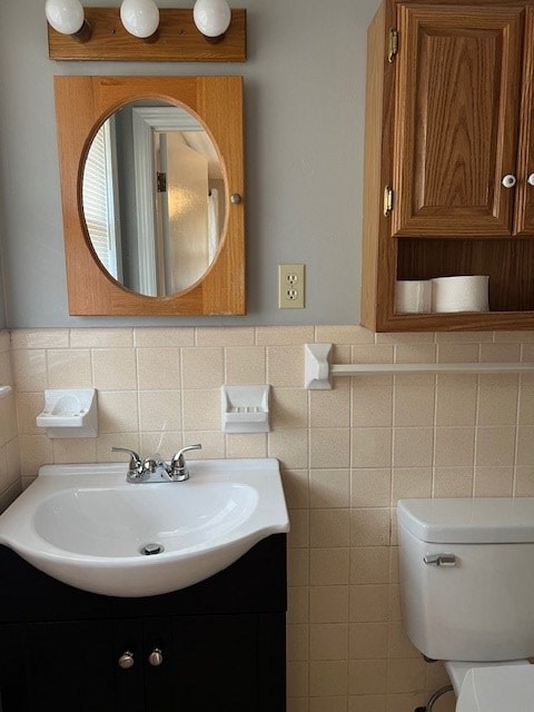 bathroom featuring vanity, toilet, and tile walls