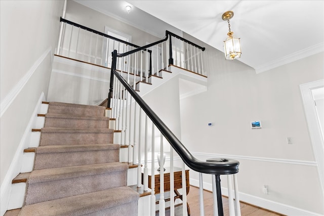 staircase featuring baseboards, wood finished floors, and ornamental molding