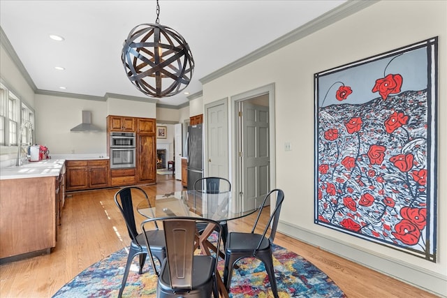 dining space with baseboards, ornamental molding, recessed lighting, light wood-style flooring, and a fireplace