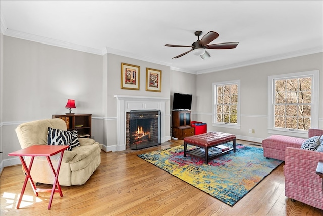 living room featuring crown molding, light wood-style flooring, a fireplace with flush hearth, and baseboards