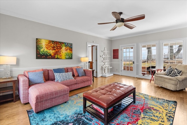 living room with a ceiling fan, crown molding, and wood finished floors