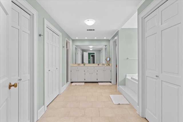 bathroom with a closet, a garden tub, visible vents, and vanity