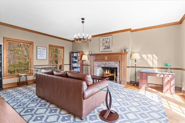 living room featuring a notable chandelier, a brick fireplace, baseboards, and wood finished floors