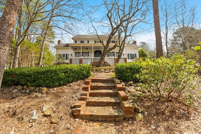 view of front of home with stairs, a porch, and a chimney