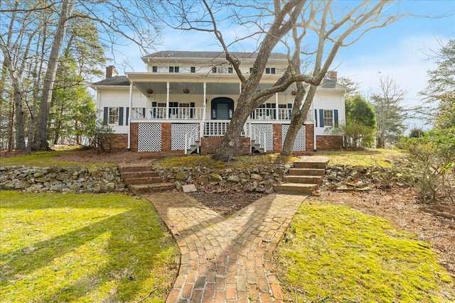 view of front of house with stairway, a front yard, covered porch, and a chimney