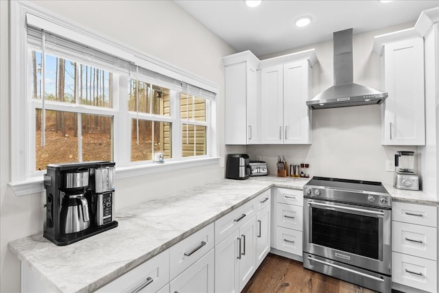 kitchen with white cabinetry, high end stainless steel range, light stone countertops, dark wood-type flooring, and wall chimney range hood