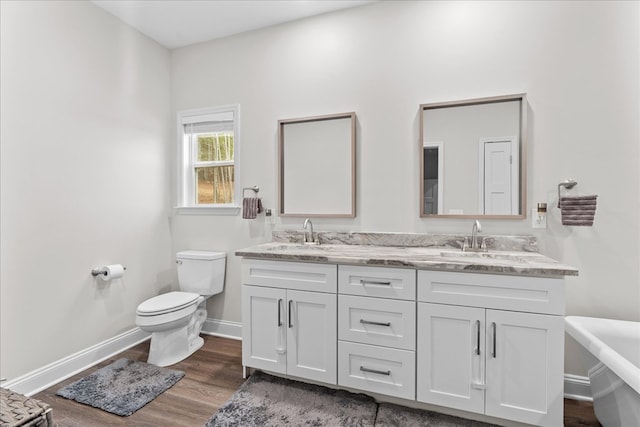 bathroom with hardwood / wood-style flooring, vanity, toilet, and a bathing tub