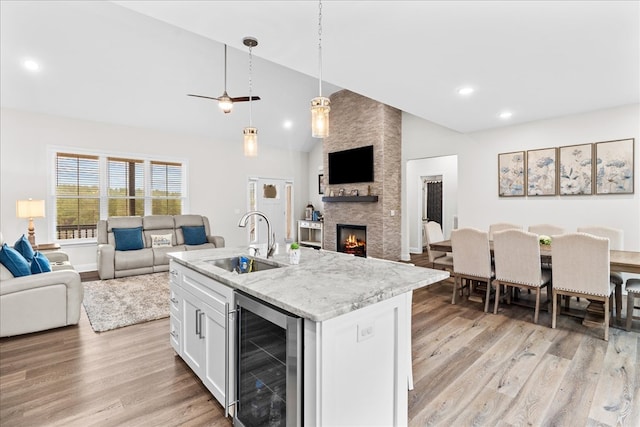 kitchen with sink, white cabinetry, wine cooler, a center island with sink, and decorative light fixtures