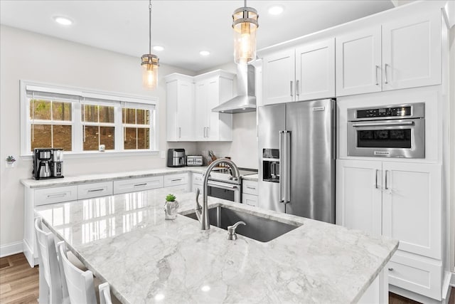 kitchen featuring pendant lighting, sink, white cabinets, light stone counters, and stainless steel appliances