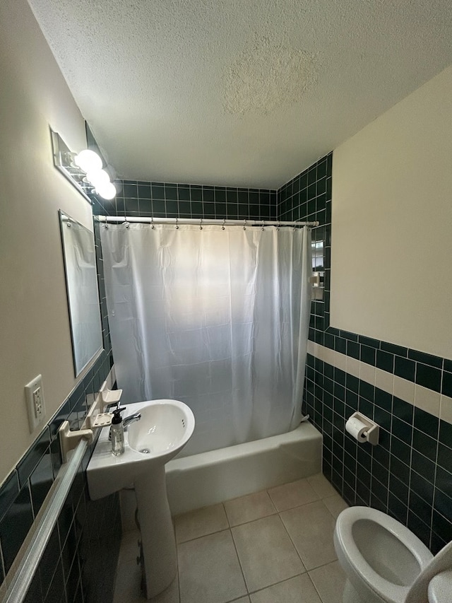 bathroom featuring tile patterned floors, toilet, tile walls, and a textured ceiling